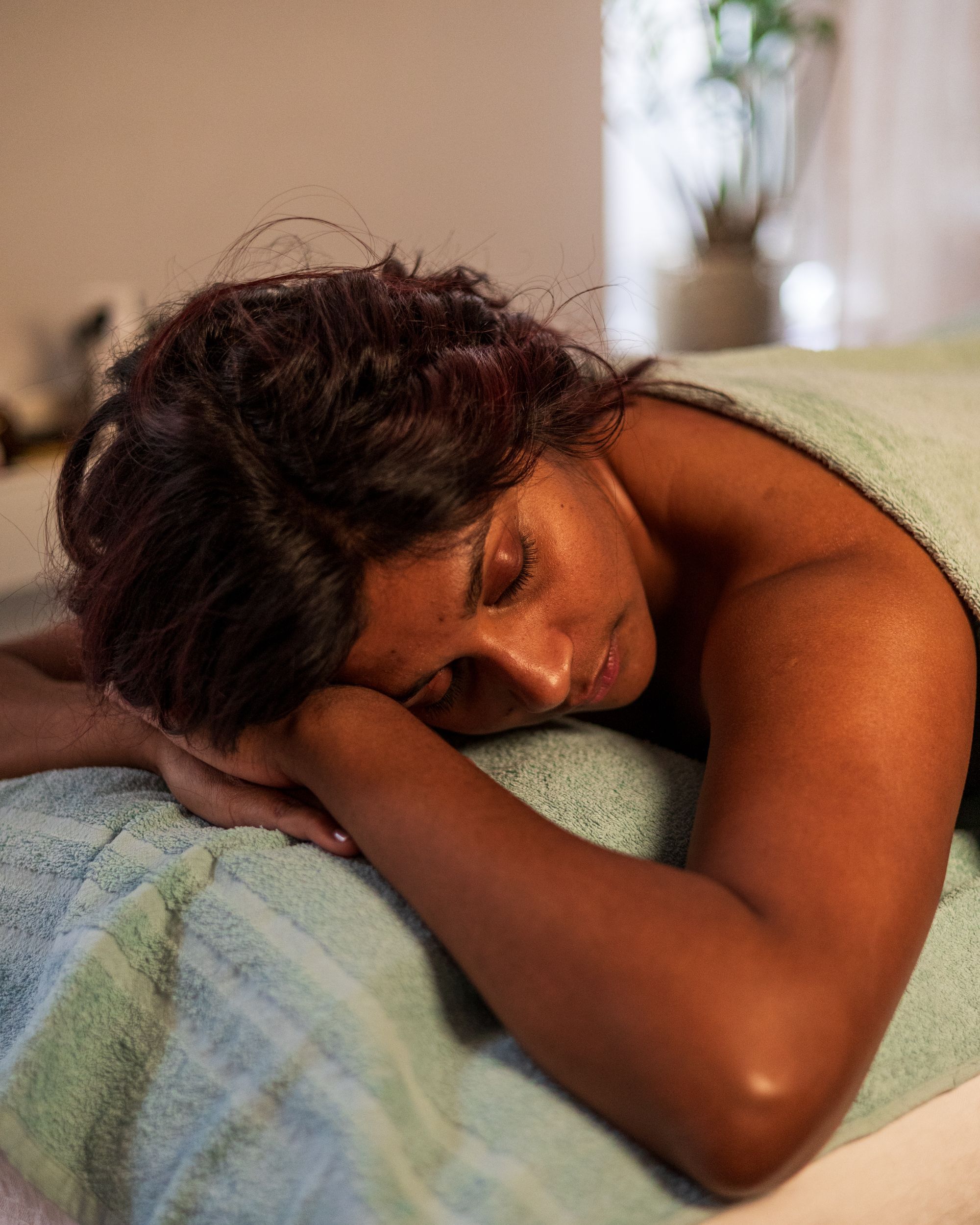 mörkhyad kvinna ligger på massagebänk och har fått ekolgisk kroppsvård från maria åkerberg