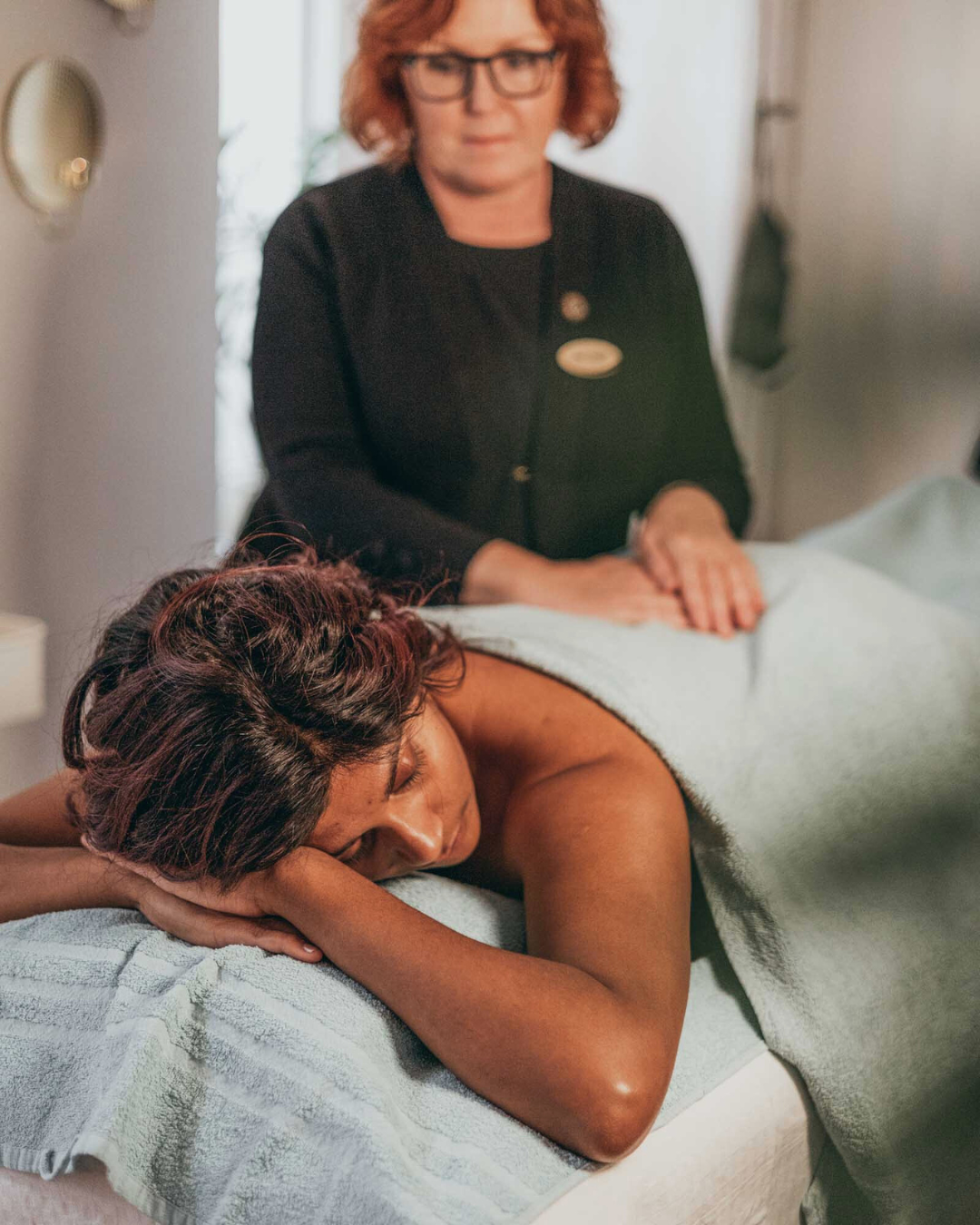 mörkhyad kvinna ligger på massagebänk och har fått ekologisk behandling av ann sköld massageterapeut